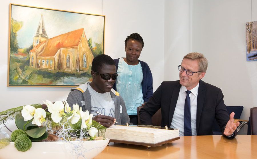 Eine Ehre für besondere Gäste (von links): Solomon Otwao und Caroline Kiyai trugen sich in das Goldene Buch der Gemeinde Wallenhorst ein, das Bürgermeister Otto Steinkamp für sie gern aufschlug. Foto: Gemeinde Wallenhorst / André Thöle