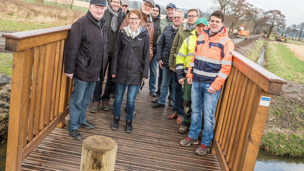 Mitglieder des Arbeitskreises Dorferneuerung, Vertreter der Gemeindeverwaltung und der Baufirmen sowie Bürgermeister Otto Steinkamp (3. von rechts) präsentieren die neue Brücke am Erftenbecksweg. Foto: Thomas Remme