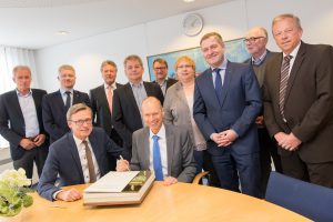 Landrat Dr. Michael Lübbersmann trägt sich im Beisein von Bürgermeister Otto Steinkamp und einigen Mitgliedern des Rates ins Goldene Buch der Gemeinde Wallenhorst ein. Foto: André Thöle