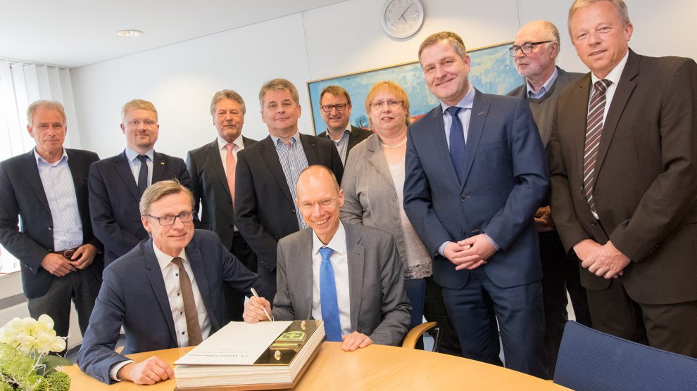 Landrat Dr. Michael Lübbersmann trägt sich im Beisein von Bürgermeister Otto Steinkamp und einigen Mitgliedern des Rates ins Goldene Buch der Gemeinde Wallenhorst ein. Foto: André Thöle