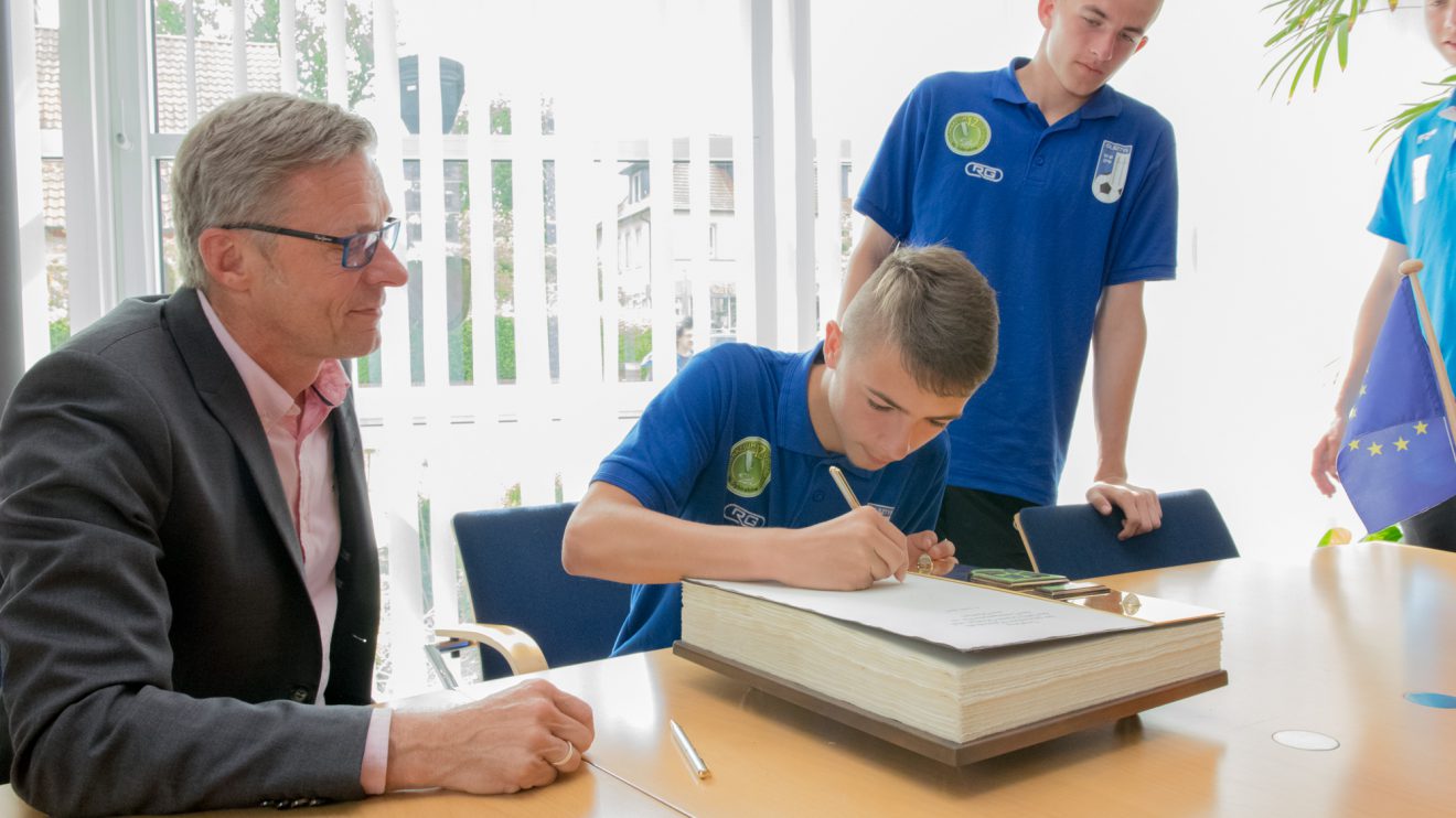 Mannschaftskapitän Kacper Zcwejko war der erste, der sich im Beisein von Bürgermeister Otto Steinkamp (links) ins Goldene Buch eintrug, seine Teamkollegen folgten. Foto: André Thöle