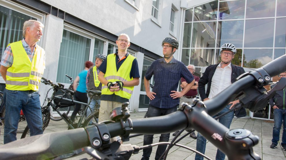 Bürgermeister Otto Steinkamp, Stefan Sprenger und Wolfgang Driehaus (von rechts) erläutern den Zweck der ersten verkehrspolitischen Radtour. Foto: André Thöle