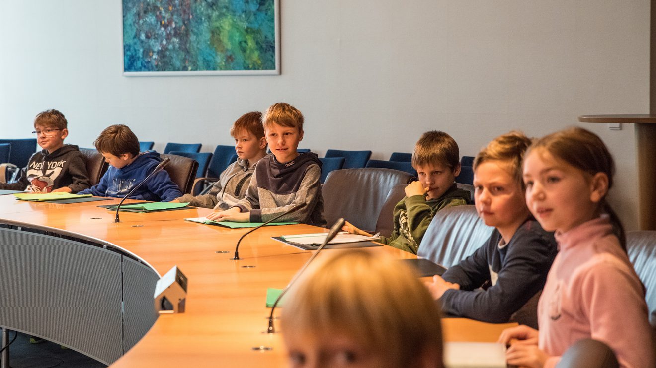 Wie die Mitglieder des Gemeinderates: mit ihren Arbeitsmappen nehmen die Kinder am runden Tisch im Sitzungssaal Platz. Foto: Thomas Remme