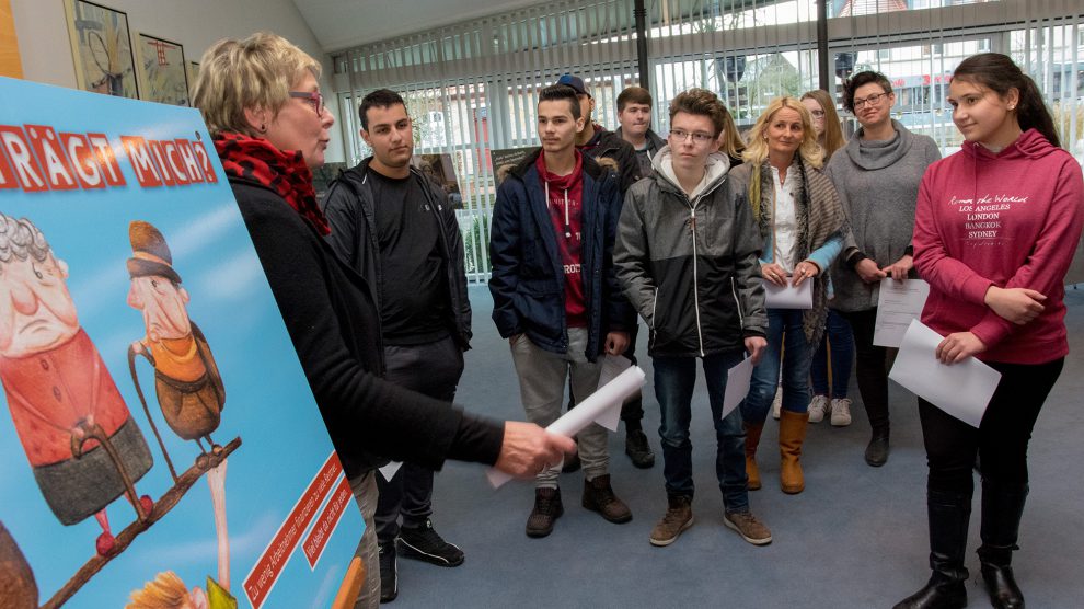 Kornelia Böert (links) erläutert die Motive der Ausstellung und diskutiert diese mit den Schülerinnen und Schülern. Foto: André Thöle