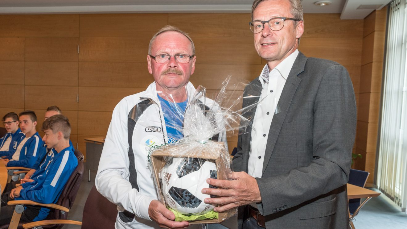 Mit Blick auf die kommende Fußballweltmeisterschaft überreicht Bürgermeister Otto Steinkamp (rechts) das passende Spielgerät als Gastgeschenk an Trainer Jerzy Budziłek. Gruppenfoto vor dem Rathaus. Foto: Thomas Remme