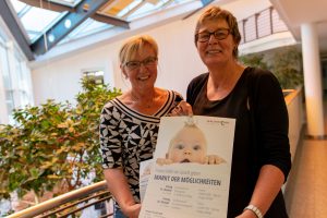 Angelika Uhlen und Kornelia Böert (von links) weisen auf den Markt der Möglichkeiten zum Thema „Frühe Hilfen“ in den Familienzentren hin. Foto: André Thöle