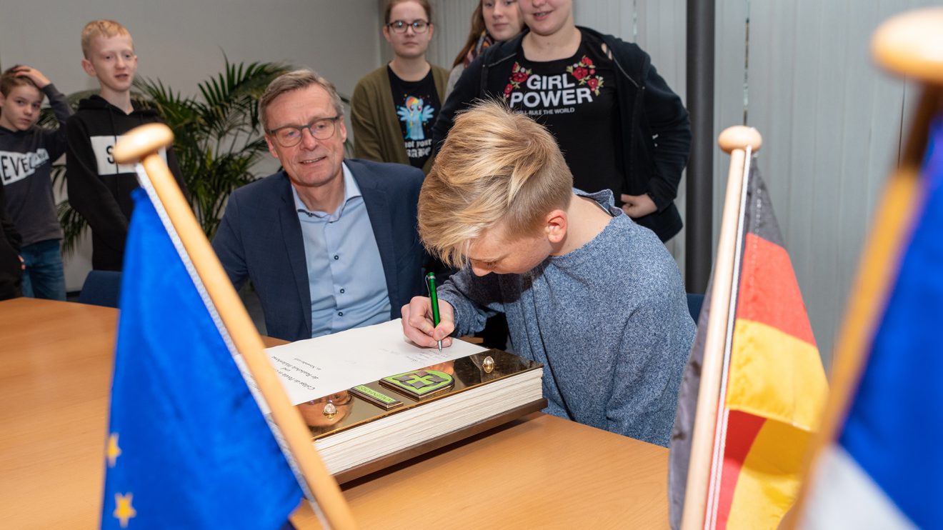 Die Schülerinnen und Schüler tragen sich im Beisein von Bürgermeister Otto Steinkamp ins Goldene Buch der Gemeinde Wallenhorst ein. Foto: Thomas Remme