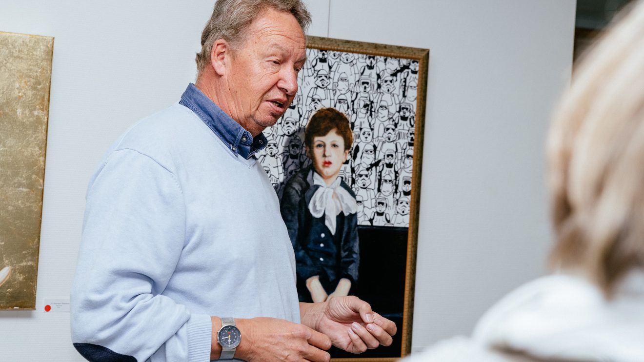 Thomas Johannsmeier erläutert den Schülerinnen und Schülern, mit welchen Materialien er arbeitet: Das Porträt „Der kleine Lord“ hat er mit wasserlöslichen Ölfarben gemalt, den Hintergrund mit einem handelsüblichen Edding gestaltet. Foto: Gemeinde Wallenhorst / Thomas Remme