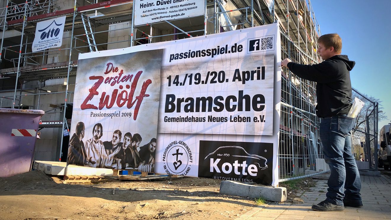 Ein Banner wird im Wallenhorster Zentrum für das Passionsspiel 2019 aufgehängt. Foto: Volker Holtmeyer