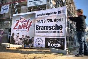 Ein Banner wird im Wallenhorster Zentrum für das Passionsspiel 2019 aufgehängt. Foto: Volker Holtmeyer