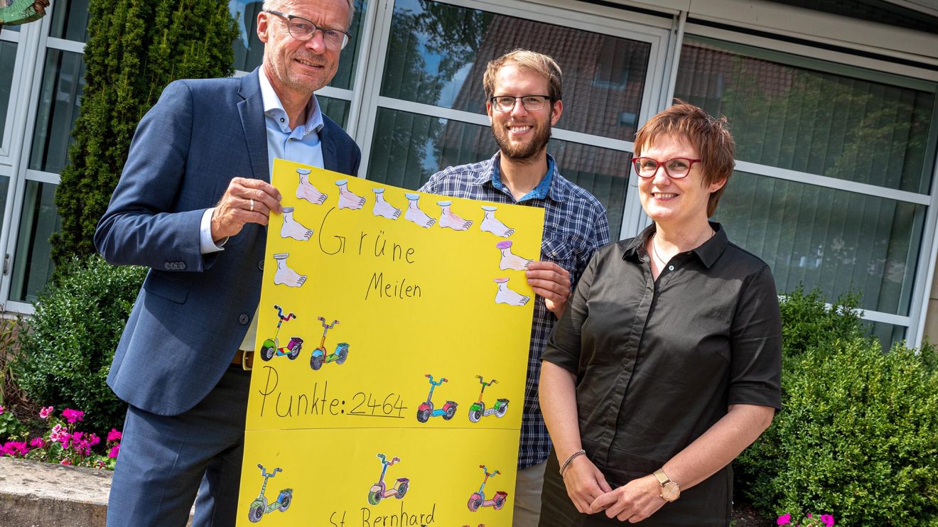 Petra Wiegmann überreicht Bürgermeister Otto Steinkamp und Klimaschutzmanager Stefan Sprenger ein Plakat mit den gesammelten „grünen Meilen“. Foto: Gemeinde Wallenhorst / Thomas Remme