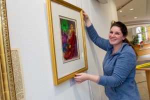 Nina Ollmert (Kunsthandlung Hülsmeier) hängt die Lithographien im Foyer des Wallenhorster Rathauses auf. Foto: Gemeinde Wallenhorst / André Thöle