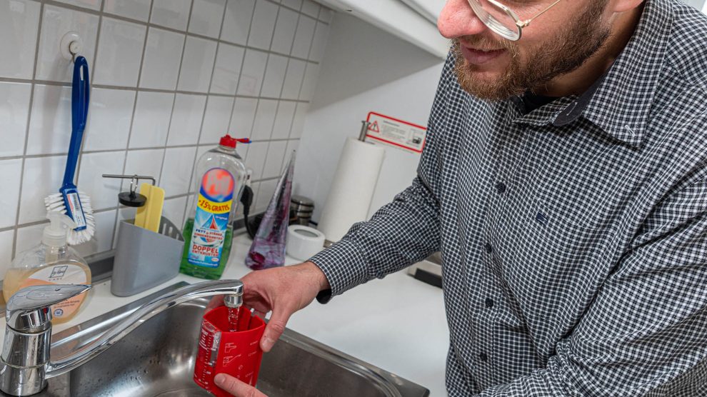 Stefan Sprenger demonstriert die Funktionsweise eines Durchflussmengen-Messbechers. Foto: Gemeinde Wallenhorst / Thomas Remme