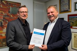 Dr. Reinhold Kassing (rechts) überreicht Bürgermeister Otto Steinkamp die VKU-Mitgliedsurkunde. Foto: Gemeinde Wallenhorst / André Thöle