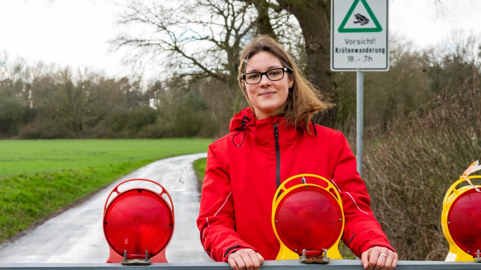 Zum Schutz von Kröten, Fröschen und Molchen werden im Außenbereich einige Straßen nachts gesperrt, wie Wallenhorsts Umweltbeauftragte Isabella Draber zeigt. Foto: André Thöle / Gemeinde Wallenhorst