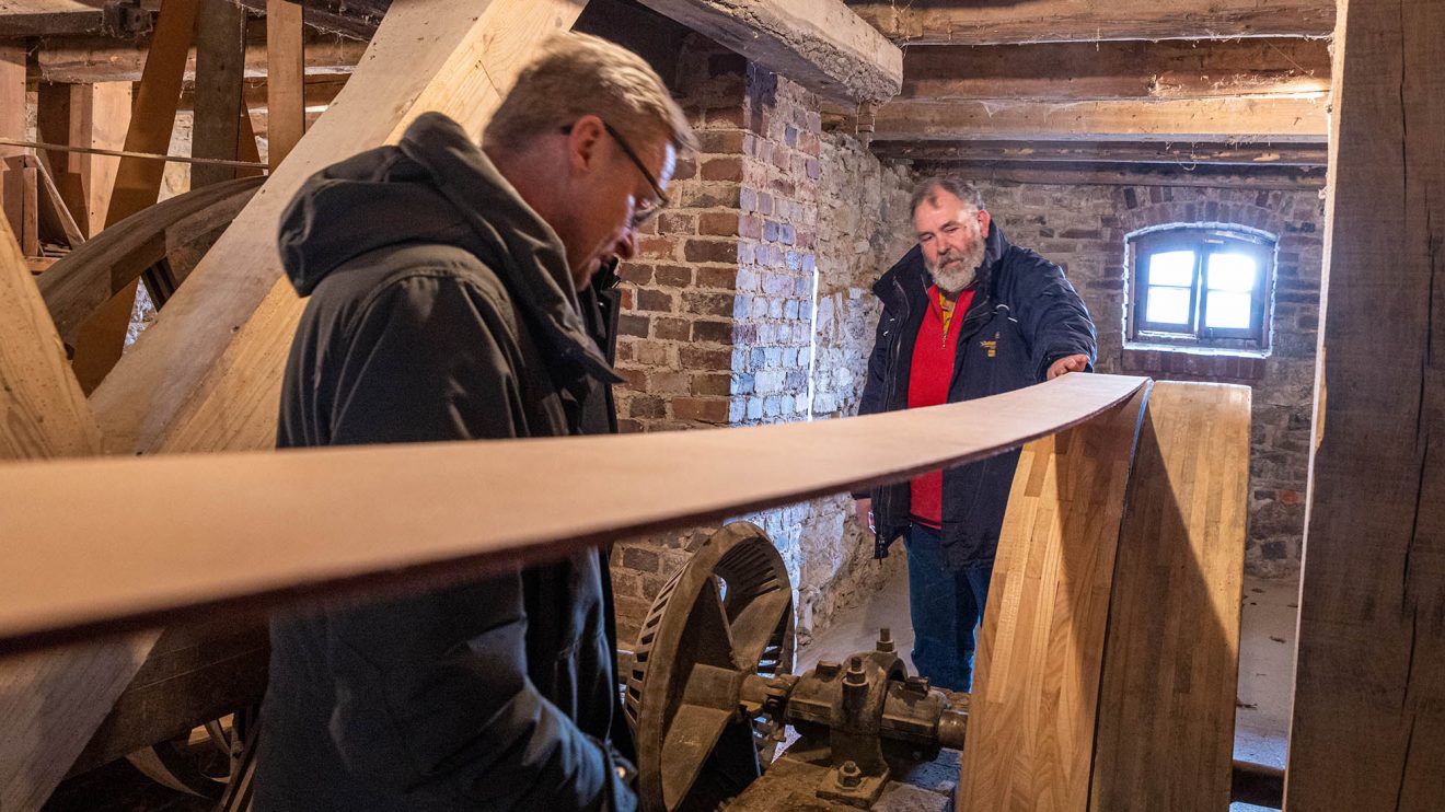 Bürgermeister Otto Steinkamp betrachtet unter fachmännischer Erläuterung durch Ansgar Vennemann die Antriebstechnik der Motormühle. Foto: Thomas Remme / Gemeinde Wallenhorst