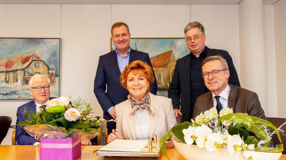 Niedersachsens Justizministerin Barbara Havliza trägt sich im Beisein von Bürgermeister Otto Steinkamp ins Goldene Buch der Gemeinde Wallenhorst ein. Der stellvertretende Bürgermeister Alfred Lindner (links) sowie die Landtagsabgeordneten Guido Pott und Clemens Lammerskitten (stehend) schauen zu. Foto: André Thöle / Gemeinde Wallenhorst