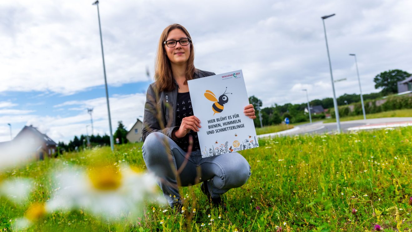 Auf Flächen wie dieser blüht es für Bienen, Hummeln und Schmetterlinge, wie Isabella Draber anhand des Hinweisschildes erklärt. Foto: André Thöle / Gemeinde Wallenhorst