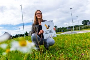 Auf Flächen wie dieser blüht es für Bienen, Hummeln und Schmetterlinge, wie Isabella Draber anhand des Hinweisschildes erklärt. Foto: André Thöle / Gemeinde Wallenhorst