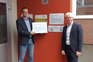 Stefan Engelshove, Kuratoriumsvorsitzender der VME-Stiftung Osnabrück-Emsland und Vice President Oil & Gas Deutschland / Betriebsleitung Siemens Energy Osnabrück (rechts) hat Schulleiter Stefan Schmidt (links) das neue Schulschild „MINT-Schule-Niedersachen – Realschule Wallenhorst 2020-2023“ im Nachgang der erfolgreichen Rezertifizierung überreicht. Foto: VME-Stiftung Osnabrück-Emsland