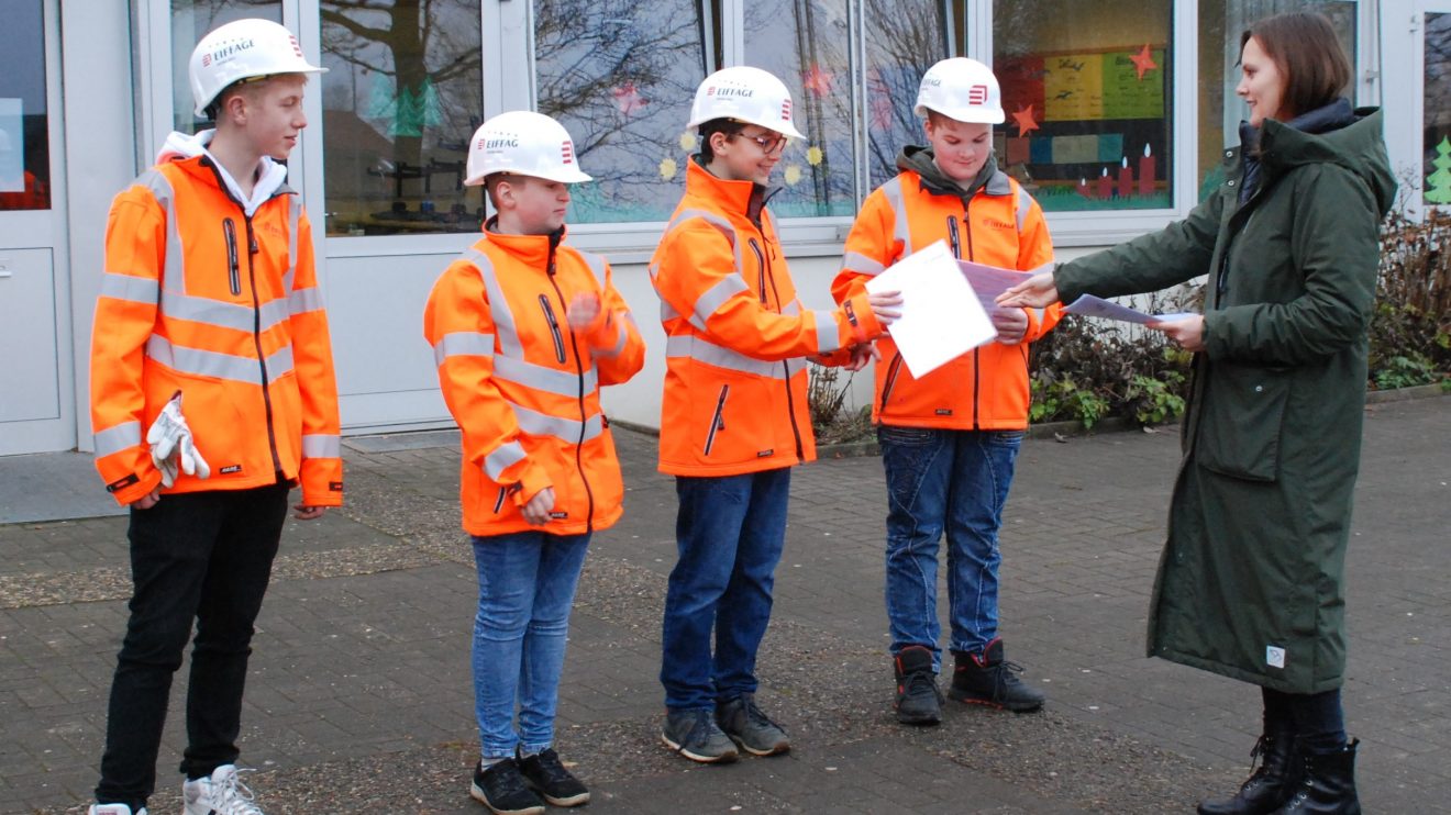 Vier Schüler der Alexanderschule in Wallenhorst haben in einer GenerationenWerkstatt mit dem Unternehmen Eiffage Infra-Nordwest eine Bodenplatte aus Natursteinen mit dem Motiv des Schullogos aus Klinkersteinen gebaut. Foto: Babette Rüscher-Ufermann / Ursachenstiftung Osnabrück