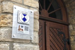 Ein neues Hinweisschild am Haupteingang der Kirche St. Josef Hollage weist ab sofort auf das Jubiläum anlässlich des 100-jährigen Bestehens der Kirchengemeinde hin. Foto: Volker Holtmeyer