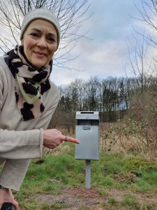 Birgit Schad zeigt den neuen Mülleimer am Parkplatz Grubenweg vor dem Piesberg. Foto: Birgit Schad