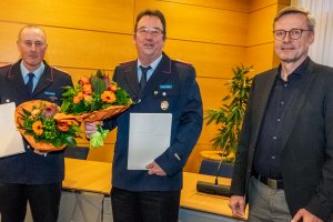 Ortsbrandmeister Ansgar Osterbrink (links) und sein Stellvertreter Lothar Gödeker nehmen die Ernennungsurkunden samt Blumen von Bürgermeister Otto Steinkamp entgegen. Foto: André Thöle / Gemeinde Wallenhorst