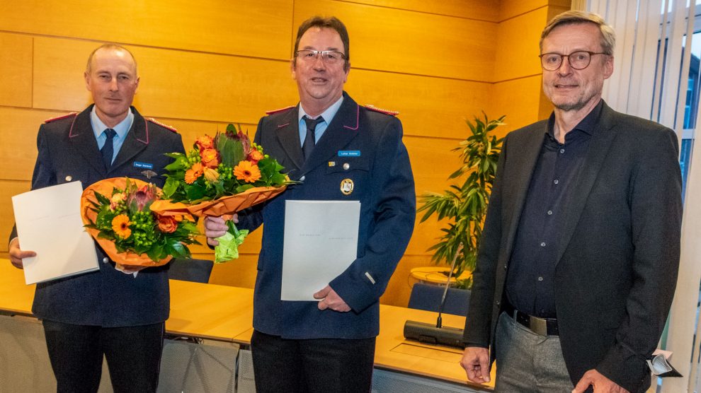 Ortsbrandmeister Ansgar Osterbrink (links) und sein Stellvertreter Lothar Gödeker nehmen die Ernennungsurkunden samt Blumen von Bürgermeister Otto Steinkamp entgegen. Foto: André Thöle / Gemeinde Wallenhorst