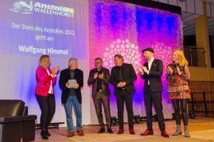 Preisträger Wolfgang Himmel (2. von links) mit dem „Stein des Anstoßes“. Gabi Münch, Bürgermeister Otto Steinkamp, Ludger Abeln, Nils-Arne Kässens und Helga Reichert (von links) gratulieren. Foto: Thomas Remme / Gemeinde Wallenhorst