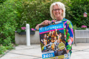 Christina Middendorp vom Familienservicebüro mit dem Plakat zum Osnabrücker Ferienpass, den auch Wallenhorster Kinder in den Sommerferien nutzen können. Foto: André Thöle / Gemeinde Wallenhorst