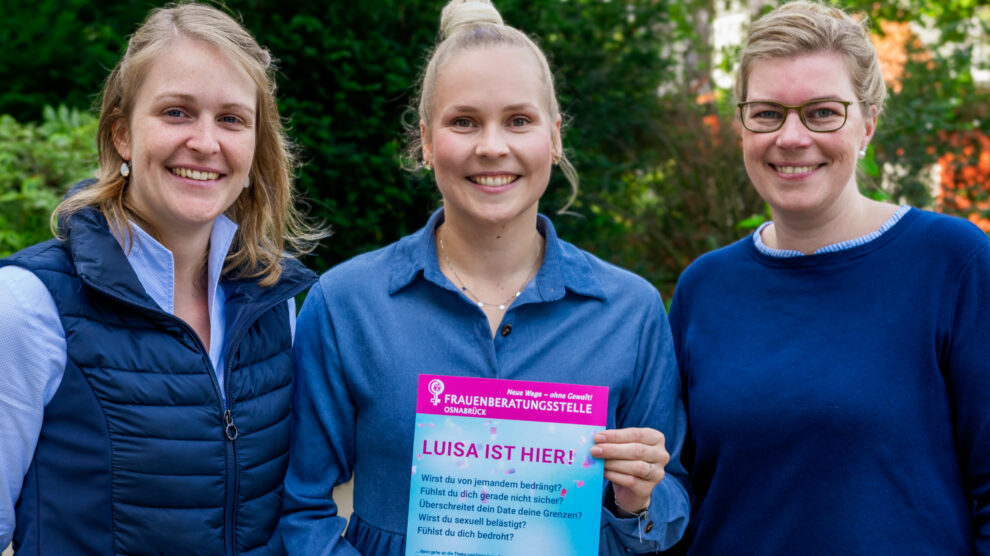 Franziska Matt, Julia Marx und Martina Unland mit einem Hinweis-Plakat auf das „Luisa ist hier!“-Konzept, das beim Hollager Oktoberfest zum Einsatz kommt. Foto: André Thöle / Gemeinde Wallenhorst