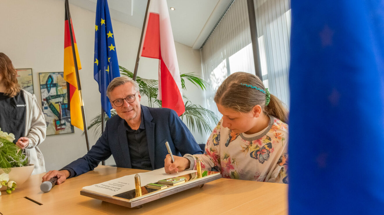 Polnische und deutsche Schülerinnen und Schüler tragen sich im Beisein von Bürgermeister Otto Steinkamp ins Goldene Buch der Gemeinde Wallenhorst ein. Foto: André Thöle / Gemeinde Wallenhorst