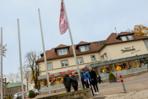 Bürgermeister Otto Steinkamp, Sabine Stenzel, André Schwegmann, Hans Stegemann und Michael Lührmann (von links) hissen die Fahne „Nein zu Gewalt gegen Frauen“ vor dem Wallenhorster Rathaus. Foto: Gemeinde Wallenhorst