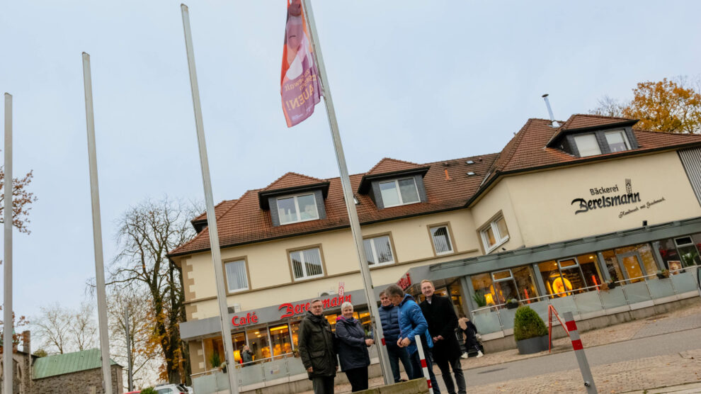 Bürgermeister Otto Steinkamp, Sabine Stenzel, André Schwegmann, Hans Stegemann und Michael Lührmann (von links) hissen die Fahne „Nein zu Gewalt gegen Frauen“ vor dem Wallenhorster Rathaus. Foto: Gemeinde Wallenhorst