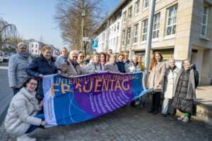 Wallenhorsts Gleichstellungsbeauftragte Leonie Winter (3. von rechts) zeigt gemeinsam mit Bürgermeister Otto Steinkamp und zahlreichen Frauen aus Ehrenamt, Politik und Verwaltung Flagge für Frauenrechte. Foto: André Thöle