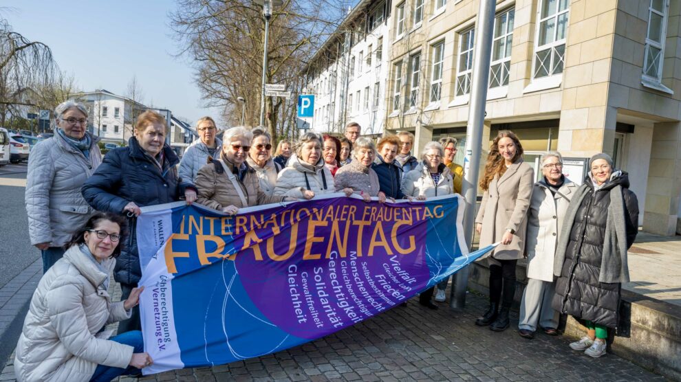 Wallenhorsts Gleichstellungsbeauftragte Leonie Winter (3. von rechts) zeigt gemeinsam mit Bürgermeister Otto Steinkamp und zahlreichen Frauen aus Ehrenamt, Politik und Verwaltung Flagge für Frauenrechte. Foto: André Thöle