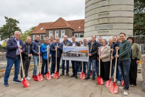 Zu spät für einen Einsatz der Schaufeln: Bürgermeister Otto Steinkamp (Mitte), Ratsmitglieder sowie Vertreter der Schule und der beteiligten Unternehmen auf der Baustelle. Foto: Gemeinde Wallenhorst / André Thöle