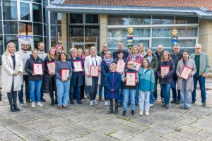Gemeinsam mit Bürgermeister Otto Steinkamp (3. von rechts) und Stefan Brune (4. von links) präsentieren die ausgezeichneten Einrichtungen ihre Urkunden. Foto: André Thöle / Gemeinde Wallenhorst